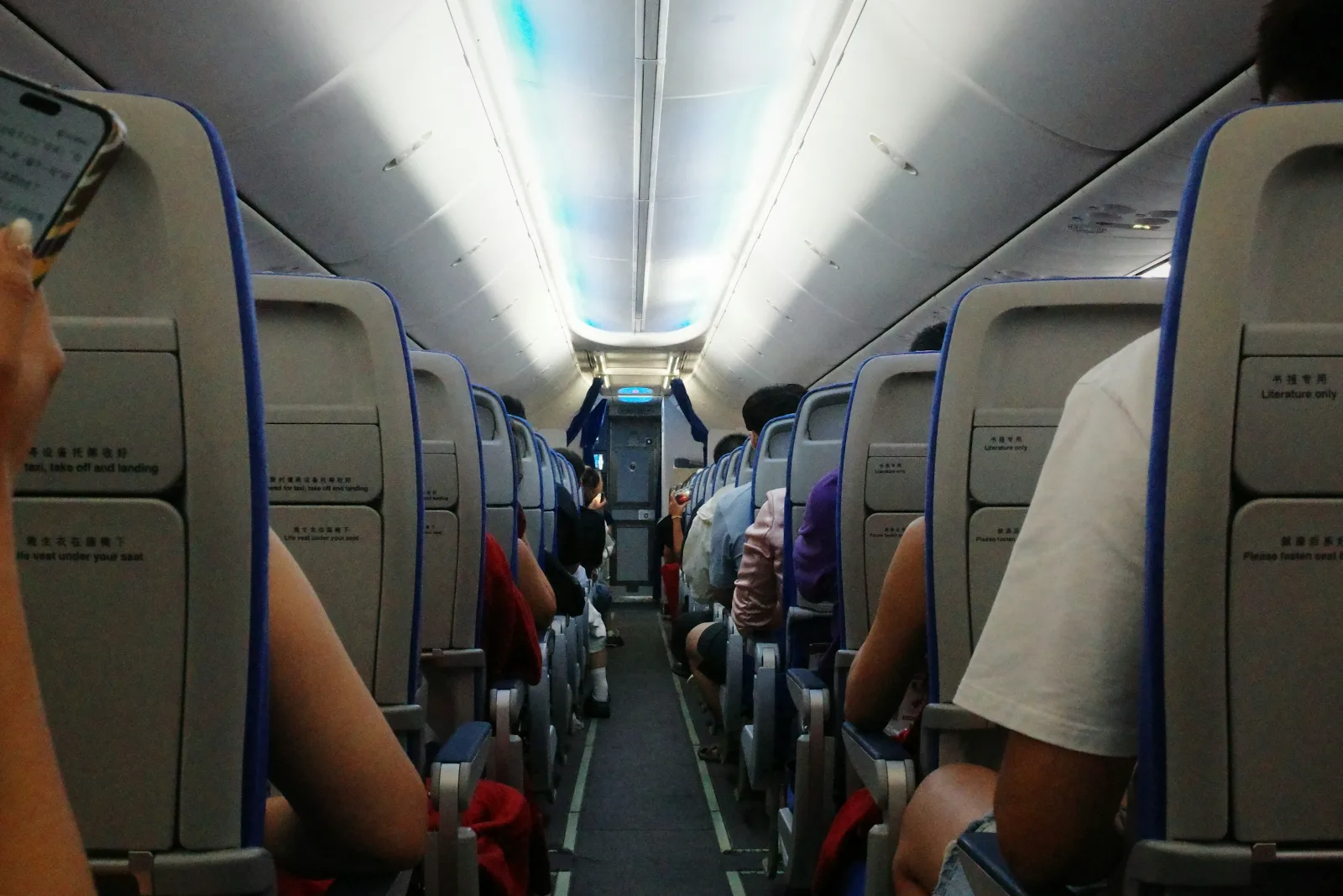 Passengers seated along the aisle of an airplane cabin