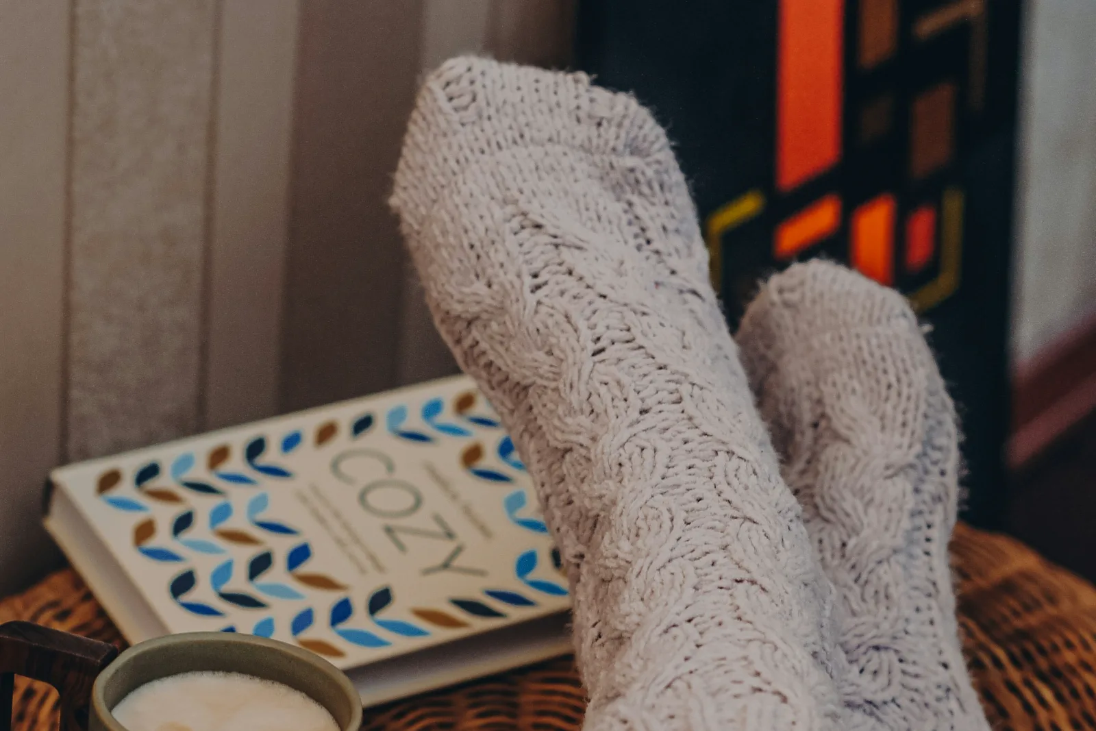 Feet in thick knit socks resting beside an open book